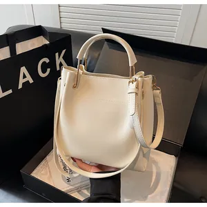Dettaglio della borsa a secchiello in pelle bianco crema con finiture in oro e box
