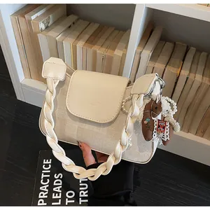 Close-up of cream shoulder bag with woven strap and embroidered horse charm detail