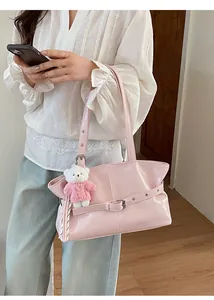 Close-up of pink leather tote bag featuring a cute white teddy bear plush keychain