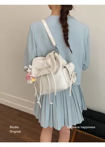 Detail view of cream leather backpack with bow drawstring and bear charm on back