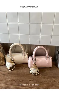 Detail of cream and pink leather cylinder bags with plush charms on a wooden desk