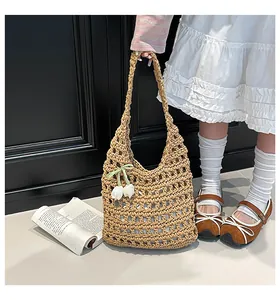 Detail of hand-woven hollow tote bag in khaki with a white tulip pendant accessory