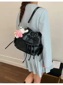 Detail of black glossy leather backpack with drawstring bow and cute rabbit charm