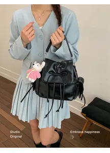 Close-up of black glossy backpack with bow ties and a cute bunny plush charm