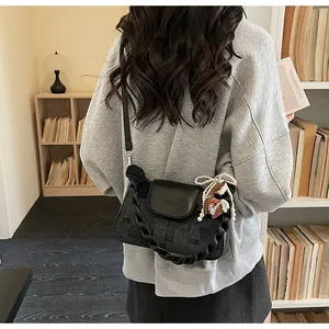Close-up of vintage black crossbody bag with mixed textures, pearl charm, and horse pendant