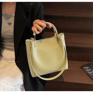 Dettaglio della borsa a secchiello in pelle verde menta con cuciture e fibbie dorate