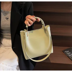 Dettaglio della borsa a secchiello verde chiaro con manici metallici e pelle testurizzata