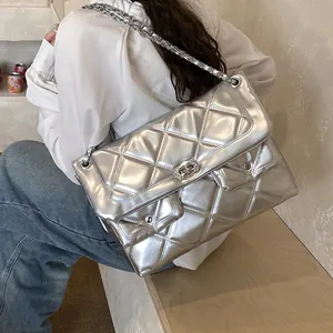 Silver quilted shoulder bag with chain strap and dual pockets shown on a model