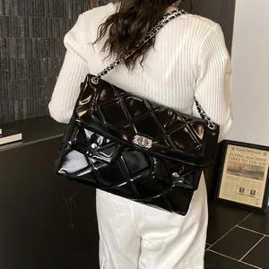 Quilted black patent leather shoulder bag with silver chain strap shown on model