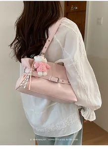 Pink patent leather tote bag with decorative buckle and cute teddy bear charm on model