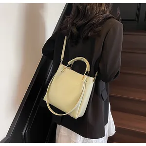 Dettaglio della borsa a secchiello minimalista con manico in metallo indossata da una modella