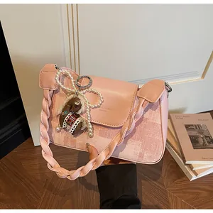 Detail of pink vintage square bag featuring braided strap and decorative horse charm