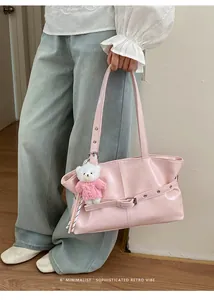 Detail of pink glossy shoulder bag with buckle strap and cute teddy bear charm accessory