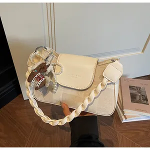 Detail of beige canvas shoulder bag with woven strap and a decorative horse charm