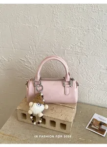 Close-up of pink cylinder handbag with soft PU texture and cute plush charm