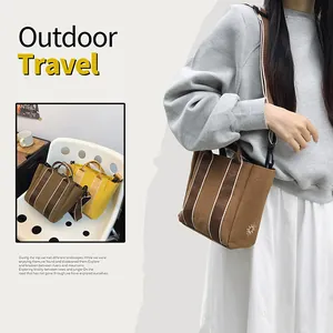 Detail of canvas bucket bag with vertical stripes, sun embroidery and wide strap