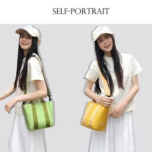 Detail of canvas bucket bags with contrast webbing handles and sun embroidery logo