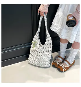 Detailed macro of white handmade crochet tote bag featuring floral pendant and woven texture