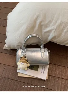 Close-up of silver cylinder handbag with plush monster charm on a stylish background