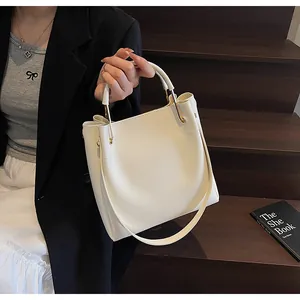 Elegante borsa a secchiello crema con dettagli dorati indossata da una modella