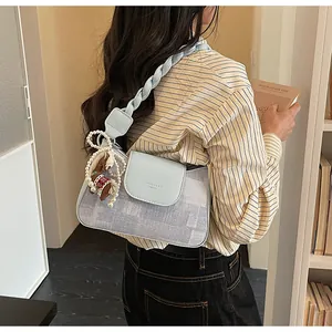 Detailed close-up of light blue patchwork shoulder bag with woven strap and pearl charm