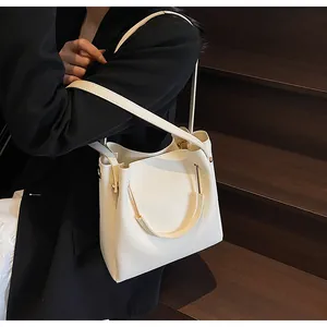 Dettaglio della borsa a secchiello bianca con manico in oro e pelle liscia