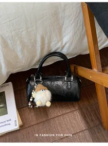 Detailed view of black Boston bag with vintage pleated texture and cute dwarf pendant