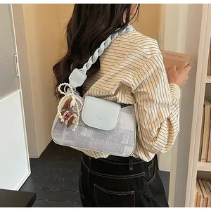 Detail of light blue crossbody bag featuring woven strap and pearl horse charm