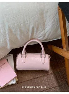 Detailed shot of pink pleated patent leather barrel bag on wooden floor