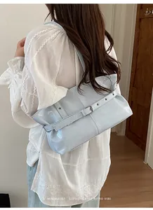Detail of light blue glossy leather shoulder bag featuring silver buckle and retro style