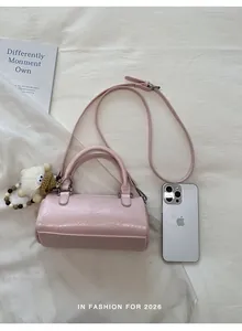 Detail of pink cylindrical leather bag with double handles and cute plush charm