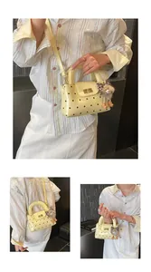 Detailansicht der gelben gepunkteten Lederhandtasche mit Plüschvogel und Riemen