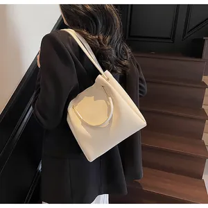 Elegante borsa a secchiello in pelle crema con manici ad anello dorati a tracolla