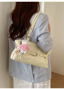 Detail of off-white patent leather shoulder bag featuring a cute teddy bear charm
