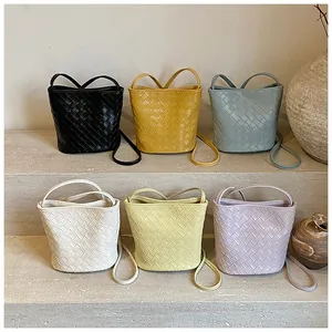 Collezione di borse a secchiello in pelle intrecciata in sei colori su gradini di pietra