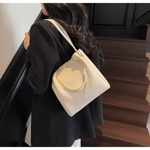 Dettaglio della borsa a secchiello bianco crema con manico dorato e trama in pelle