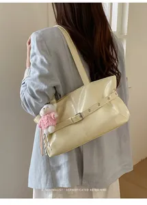Detail of cream glossy leather tote bag with silver buckle and cute plush bear charm