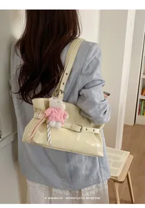 Detail of cream pleated faux leather tote bag with a pink teddy bear charm accessory
