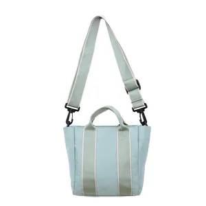 Detail view of mint green canvas bucket bag featuring wide adjustable strap and handles