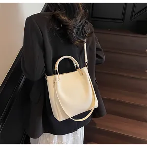 Vista posteriore di una modella con borsa a secchiello off-white su scale in legno scuro