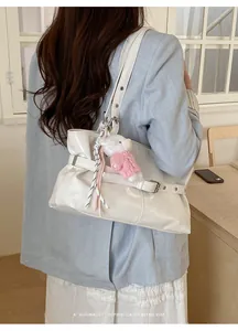 Detail of white PU leather tote with buckle accents and a cute plush bear charm