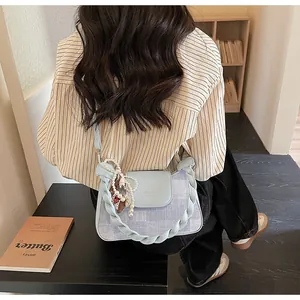 Detail of light blue leather and denim patchwork bag with pearl charm and woven handle