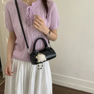Black vintage mini Boston bag with plush charm and adjustable strap shown on model