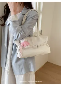 Detail of white patent leather tote bag with silver buckle and cute plush bear charm