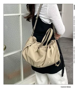 Detailed view of apricot pleated tote bag with adjustable strap worn by a model