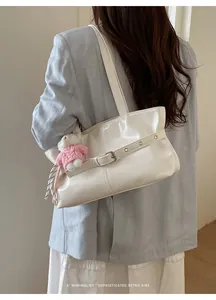 Minimalist white patent leather tote bag with a pink bear charm shown on model