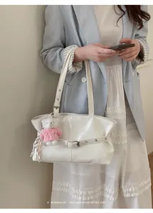 Close-up of white tote bag with bear charm, silk scarf, and decorative metal eyelet belt