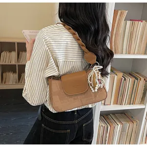 Detail view of vintage brown crossbody bag featuring wide woven strap and cute bear pendant