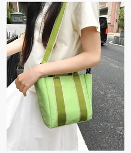 Detail of neon green canvas bucket bag with contrast webbed handles and wide strap