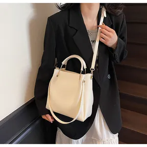 Elegante borsa a secchiello crema a tracolla su modella con gonna a pieghe